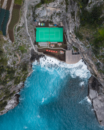 Aerial view of a vibrant green sports field nestled between rugged cliffs and the turquoise sea a stark contrast of nature and recreation Laurito Campania Italy. Aerial view of a vibrant green sports field nestled between rugged cliffs and the turquoise sea a stark contrast of nature and recreation Laurito Campania Italy.