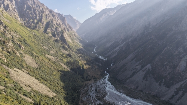 Aerial view of Ala Archa National Park featuring a winding river flowing through a deep mountain valley with steep rocky slopes and lush green vegetation Bishkek Chuy Region Kyrgyzstan. Aerial view of Ala Archa National Park featuring a winding river flowing through a deep mountain valley with steep rocky slopes and lush green vegetation Bishkek Chuy Region Kyrgyzstan.