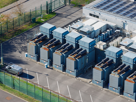 Aerial view of a data center featuring large industrial cooling units solar panels on the roof and a van parked in the lot United Kingdom.