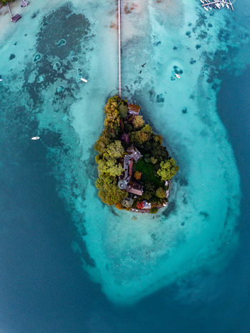 Aerial view of the small island with a historic villa in the middle of the turquoise waters of Attersee connected by a long wooden pier in Vocklabruck District Upper Austria Austria.