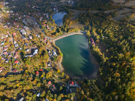 Aerial view of Velka Vindsachta and Evickino lakes surrounded by autumn forests and residential houses in Stiavnicke Bane Banskobystricky kraj Slovakia.