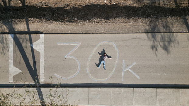 Golan Heights Israel 01 February 2025 Aerial view of a person lying on a road inside a chalk drawn 30k sign with long shadows cast across the asphalt surface. Golan Heights Israel 01 February 2025 Aerial view of a person lying on a road inside a chalk drawn 30k sign with long shadows cast across the asphalt surface.