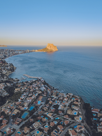 Aerial view of the Penyal d Ifac rock formation rising above the Mediterranean Sea with coastal residential areas and swimming pools in Calp Valencian Community Spain. Aerial view of the Penyal d Ifac rock formation rising above the Mediterranean Sea with coastal residential areas and swimming pools in Calp Valencian Community Spain.