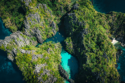 Aerial view of Big Lagoon featuring turquoise waters surrounded by dramatic limestone cliffs and lush tropical vegetation in El Nido Bay Philippines. Aerial view of Big Lagoon featuring turquoise waters surrounded by dramatic limestone cliffs and lush tropical vegetation in El Nido Bay Philippines.