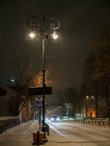 View of a street lamp illuminating a snowy street during a winter night in Vilnius Vilnius County Lithuania. View of a street lamp illuminating a snowy street during a winter night in Vilnius Vilnius County Lithuania.
