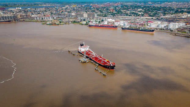 Aerial view of a large oil tanker docked at the industrial port facility with storage tanks and urban infrastructure in the background in Lagos Lagos Nigeria.