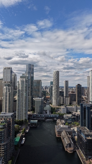 London United Kingdom 16 June 2026 Aerial view of Canary Wharf skyscrapers and modern residential towers overlooking the water under a cloudy sky.