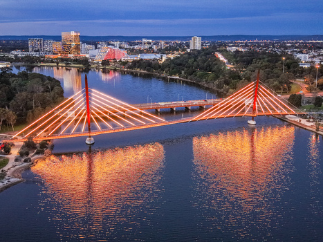 Aerial view of the illuminated Boorloo Bridge spanning the Swan River at twilight with the city skyline in the background East Perth Western Australia Australia.