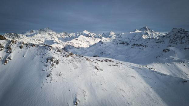 Aerial view of snow capped peaks piercing the sky a pristine white canvas etched with shadows and sunlight creating a majestic winter panorama Anniviers Valais Switzerland.
