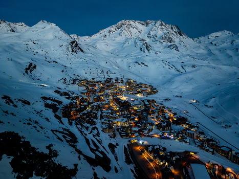 Aerial view of a village nestled amongst snow covered peaks glows warmly against the twilight sky Val Thorens Auvergne Rh&ocirc;ne Alpes France.