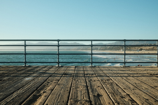 View of Santa Monica Pier wooden boardwalk with metal railings overlooking the Pacific Ocean and sandy beach Santa Monica California United States. View of Santa Monica Pier wooden boardwalk with metal railings overlooking the Pacific Ocean and sandy beach Santa Monica California United States.