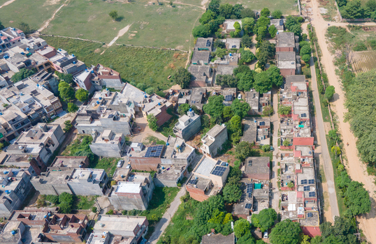 Lahore Punjab Pakistan 08 September 2026 Aerial view of a dense residential neighborhood featuring flat roofed houses solar panels and surrounding greenery.
