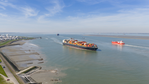 Terneuzen Netherlands 08 April 2026 Aerial view of a large container ship and a red tanker navigating the Western Scheldt waterway near industrial storage facilities. Terneuzen Netherlands 08 April 2026 Aerial view of a large container ship and a red tanker navigating the Western Scheldt waterway near industrial storage facilities.