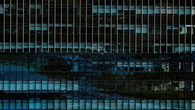 Aerial view of commercial highrise building facade with reflective glass windows and metal grid structure in Iceland.