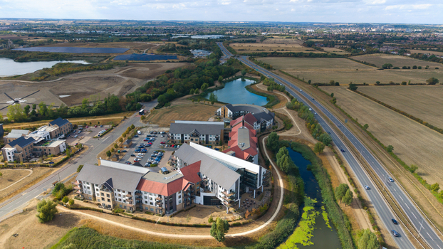 Aerial view of Wixams Retirement Village featuring modern architecture with red tiled roofs surrounded by green spaces small lakes and a highway in Bedford England United Kingdom.