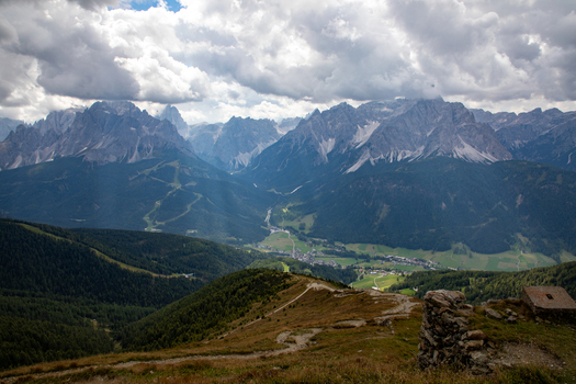 Aerial view of Dolomites mountain range with dramatic peaks lush green valleys and scattered clouds under a bright sky in Rocca Pietore Veneto Italy.