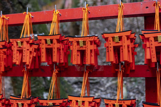View of small orange torii gate votive tablets with handwritten messages hanging on a red wooden rack at the Senbon Torii in Kyoto Kyoto Japan.