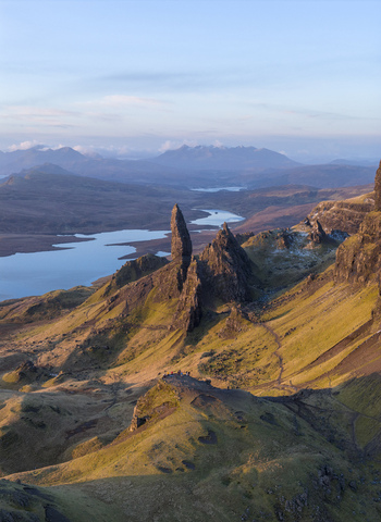 Aerial view of The Storr rock formation with jagged pinnacles and rolling green hills overlooking distant lochs in Isle of Skye Scotland United Kingdom. Aerial view of The Storr rock formation with jagged pinnacles and rolling green hills overlooking distant lochs in Isle of Skye Scotland United Kingdom.