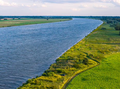 Aerial view of the Vistula River flowing through lush green fields and meadows in Pomeranian Voivodeship Poland. Aerial view of the Vistula River flowing through lush green fields and meadows in Pomeranian Voivodeship Poland.