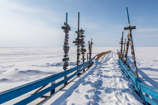 View of Goryachiye Istochniki Khakusy with wooden signposts on a snow covered pier leading onto the frozen surface of Lake Baikal in Severobaykalskiy Rayon Respublika Buryatiya Russia. View of Goryachiye Istochniki Khakusy with wooden signposts on a snow covered pier leading onto the frozen surface of Lake Baikal in Severobaykalskiy Rayon Respublika Buryatiya Russia.