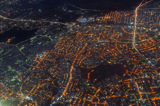 Aerial view of the illuminated cityscape at night featuring dense urban grids glowing street lights and busy traffic arteries winding through the metropolitan area in Karachi Sindh Pakistan.