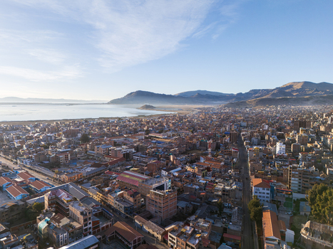 Aerial view of the city of Puno with dense urban buildings terracotta rooftops and distant mountains on the shores of Lake Titicaca in Puno Puno Peru.