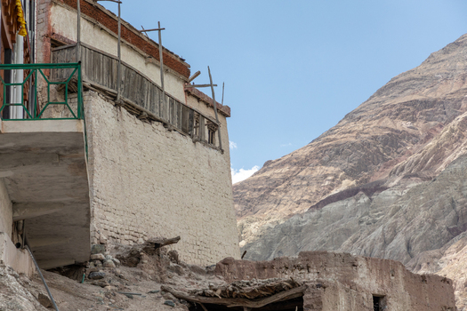 View of the traditional architecture of Charasa Gonpa with wooden balconies against a rugged mountain landscape in Charasa Ladakh India.
