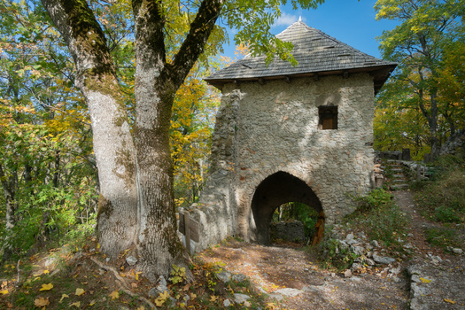 View of the historic stone gatehouse of Castle Muran surrounded by vibrant autumn trees and a forest path in Muran Banska Bystrica Regio Slovakia. View of the historic stone gatehouse of Castle Muran surrounded by vibrant autumn trees and a forest path in Muran Banska Bystrica Regio Slovakia.