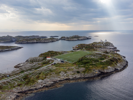 Aerial view of a football field on a rocky island with the sun s rays reflecting off the water Henningsvær Nordland Norway. Aerial view of a football field on a rocky island with the sun s rays reflecting off the water Henningsvær Nordland Norway.