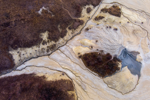 Aerial view of Vulcanii Noroiosi Paclele Mari showing unique mud volcano formations with grey craters arid textured soil and surrounding vegetation in Paclele Buzau County Romania.