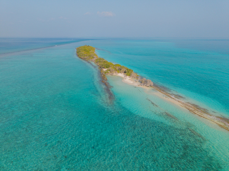 Aerial view of the island s slender sandy finger reaching out into the turquoise embrace of the sea Dhidhdhoo Thiladhunmathi Atoll Maldives.