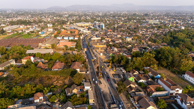 Aerial view of road construction work in a residential area with houses and trees in Indonesia. Aerial view of road construction work in a residential area with houses and trees in Indonesia.