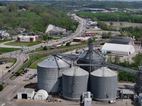 Aerial view of large industrial grain silos situated near a winding road and lush green hills in Aurora Indiana United States. Aerial view of large industrial grain silos situated near a winding road and lush green hills in Aurora Indiana United States.