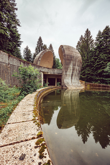 View of the brutalist concrete monument at the Korcanica Memorial Zone reflecting in a pool of water in Sanski Most Federation of Bosnia Bosnia and Herzegovina. View of the brutalist concrete monument at the Korcanica Memorial Zone reflecting in a pool of water in Sanski Most Federation of Bosnia Bosnia and Herzegovina.