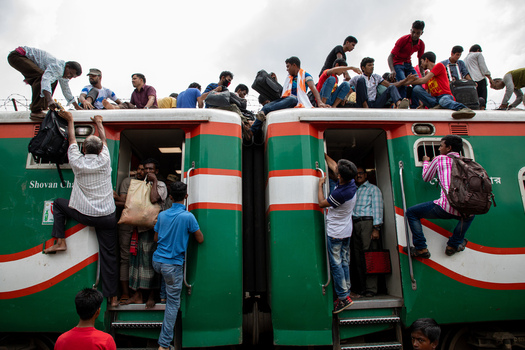 Dhaka Bangladesh 14 June 2018 View of the crowded Airport Railway Station with passengers sitting on the roof and hanging from the doors of a green and red train. Dhaka Bangladesh 14 June 2018 View of the crowded Airport Railway Station with passengers sitting on the roof and hanging from the doors of a green and red train.