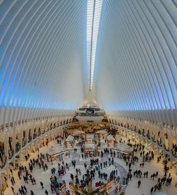 View of the Oculus at the World Trade Center with its iconic white rib structure and high vaulted ceiling filled with people walking through the terminal in New York New York United States.