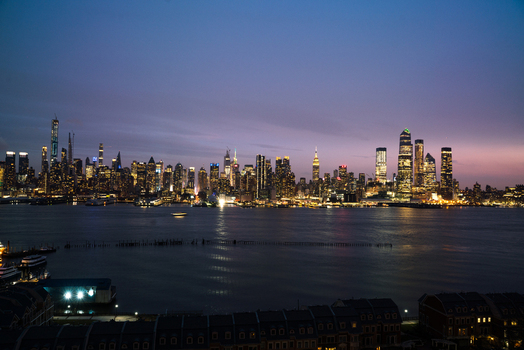 View of the illuminated New York City skyline across the Hudson River at twilight with glowing skyscrapers and calm water in the foreground United States of America. View of the illuminated New York City skyline across the Hudson River at twilight with glowing skyscrapers and calm water in the foreground United States of America.