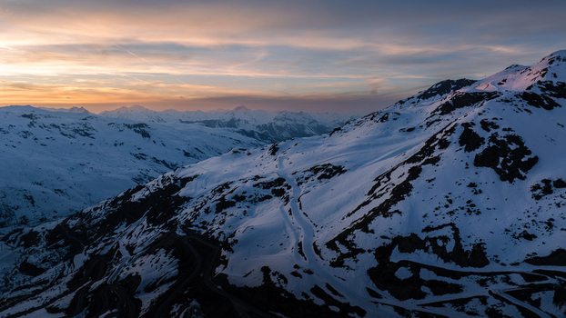 Aerial view of snow capped mountains basking in the warm glow of the setting sun the peaks casting long shadows across the serene landscape Val Thorens Auvergne Rh&ocirc;ne Alpes France.