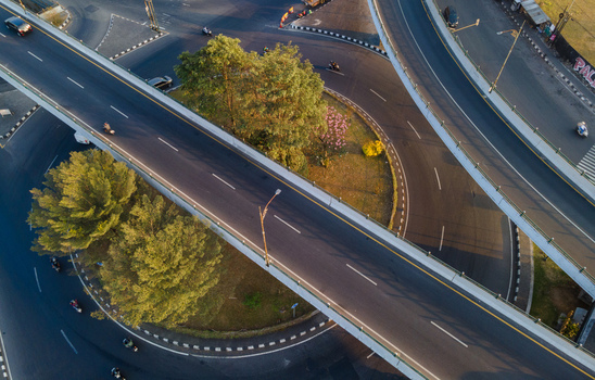 Aerial view of a highway interchange and roundabout with lush green trees and traffic in Yogyakarta Special Region of Yogyakarta Indonesia. Aerial view of a highway interchange and roundabout with lush green trees and traffic in Yogyakarta Special Region of Yogyakarta Indonesia.