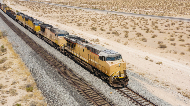 Aerial view of a freight train traveling along tracks through a vast desert landscape in the United States.