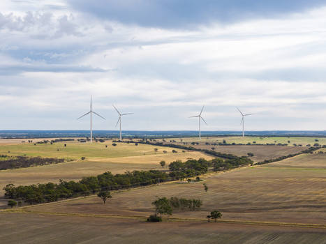 Aerial view of wind turbines standing in the vast rural landscape with rolling fields and scattered trees under a cloudy sky in Kiata Victoria Australia. Aerial view of wind turbines standing in the vast rural landscape with rolling fields and scattered trees under a cloudy sky in Kiata Victoria Australia.