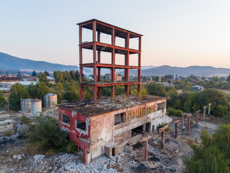 Aerial view of an abandoned industrial building with a prominent red steel frame structure surrounded by overgrown vegetation and debris in Velingrad Pazardzhik Bulgaria. Aerial view of an abandoned industrial building with a prominent red steel frame structure surrounded by overgrown vegetation and debris in Velingrad Pazardzhik Bulgaria.