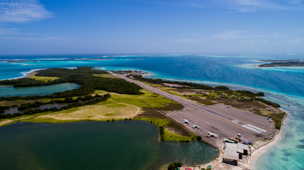 Aerial view of Los Roques archipelago featuring an airport runway surrounded by turquoise Caribbean waters and lagoons under a clear sky. Los Roques Dependencias Federales Venezuela. Aerial view of Los Roques archipelago featuring an airport runway surrounded by turquoise Caribbean waters and lagoons under a clear sky. Los Roques Dependencias Federales Venezuela.