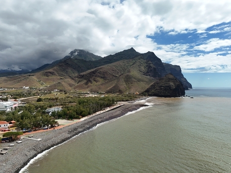 Aerial view of the rugged coastline meeting the vast ocean under a sky of contrasting clouds Puerto de la Aldea Canarias Spain. Aerial view of the rugged coastline meeting the vast ocean under a sky of contrasting clouds Puerto de la Aldea Canarias Spain.