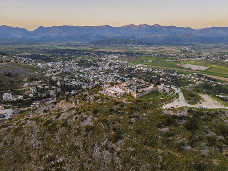 Aerial view of Lekuresi Castle perched on a hilltop overlooking the town of Saranda with mountains in the background at sunset in Saranda Vlore County Albania. Aerial view of Lekuresi Castle perched on a hilltop overlooking the town of Saranda with mountains in the background at sunset in Saranda Vlore County Albania.