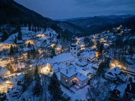 Aerial view of the historic church and illuminated houses nestled in a snow covered mountain valley at night Spania Dolina Banska Bystrica Region Slovakia. Aerial view of the historic church and illuminated houses nestled in a snow covered mountain valley at night Spania Dolina Banska Bystrica Region Slovakia.