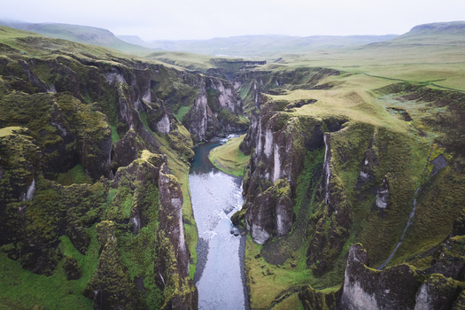 Aerial view of Fjadrargljufur canyon with its steep moss covered cliffs and a winding river under an overcast sky Skaftarhreppur Iceland. Aerial view of Fjadrargljufur canyon with its steep moss covered cliffs and a winding river under an overcast sky Skaftarhreppur Iceland.