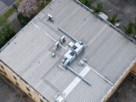 Melbourne VIC Australia 25 September 2026 Aerial view of the corrugated metal roof of an industrial building featuring multiple HVAC units ventilation systems and surrounding trees.