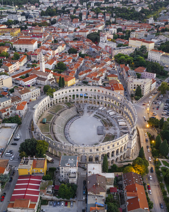 Aerial view of Pula Arena surrounded by historic stone buildings terracotta rooftops and city streets in Pula Istarska zupanija Croatia. Aerial view of Pula Arena surrounded by historic stone buildings terracotta rooftops and city streets in Pula Istarska zupanija Croatia.