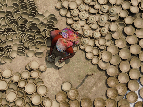 Joypurhat Bangladesh 28 September 2026 Aerial view of a woman in a colorful sari crafting clay pottery surrounded by numerous drying bowls and lids on the ground. Joypurhat Bangladesh 28 September 2026 Aerial view of a woman in a colorful sari crafting clay pottery surrounded by numerous drying bowls and lids on the ground.